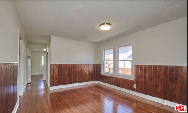 empty room featuring hardwood / wood-style floors and wooden walls