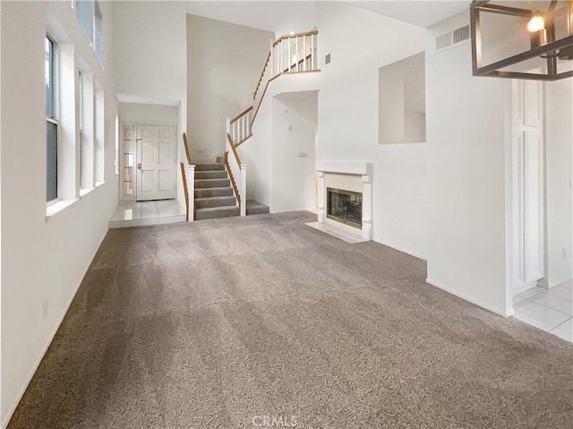 unfurnished living room with a towering ceiling and light colored carpet