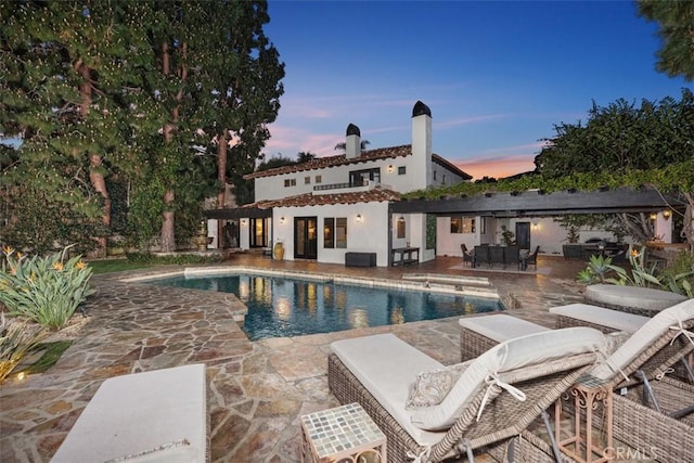 pool at dusk featuring an outdoor pool and a patio
