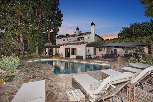 pool at dusk featuring a patio