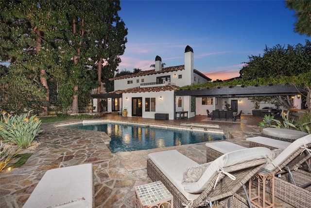 pool at dusk featuring a patio and an outdoor pool