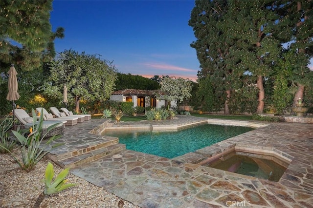 outdoor pool with a patio area, an in ground hot tub, and an outdoor structure