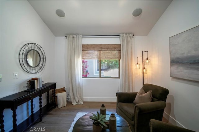 living area featuring baseboards, lofted ceiling, and wood finished floors