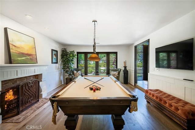 game room with a fireplace, pool table, wood finished floors, and wainscoting