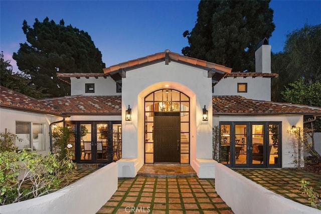 view of exterior entry featuring a tile roof, french doors, and stucco siding