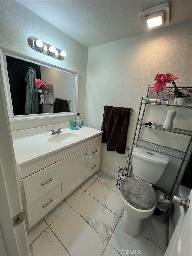 full bathroom featuring a textured wall, toilet, marble finish floor, a textured ceiling, and vanity