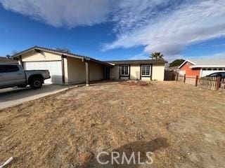 ranch-style home with a garage, concrete driveway, and fence