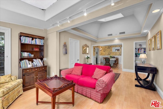 living room with rail lighting, vaulted ceiling, and light hardwood / wood-style flooring