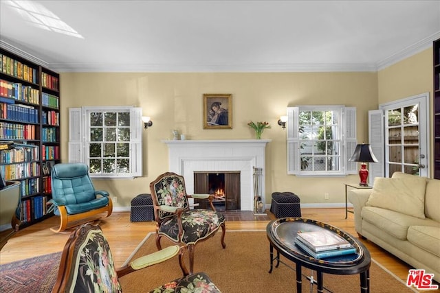 living room with ornamental molding, plenty of natural light, a brick fireplace, and light hardwood / wood-style flooring