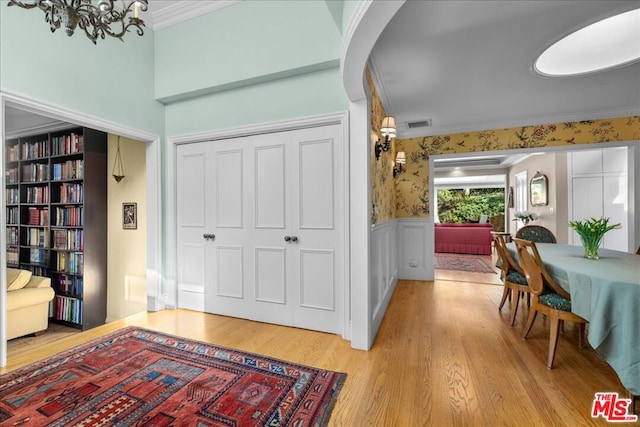 interior space with crown molding, a notable chandelier, and light hardwood / wood-style flooring