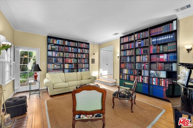 living area with hardwood / wood-style flooring and crown molding