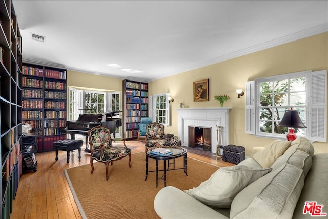 living room featuring ornamental molding, wood-type flooring, and a fireplace