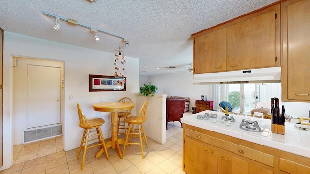 kitchen with white gas stovetop, tile countertops, and a textured ceiling