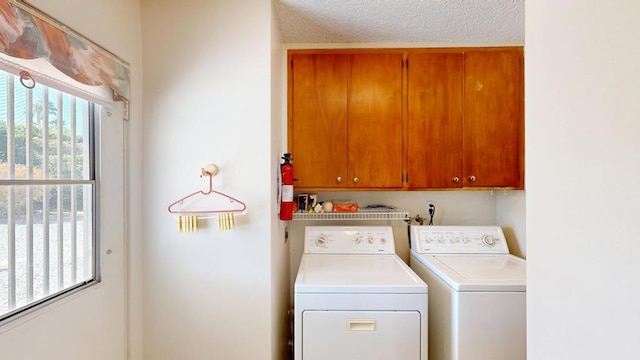 washroom featuring cabinets, washer and dryer, and a textured ceiling