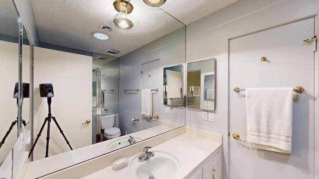 bathroom with vanity, toilet, and a textured ceiling