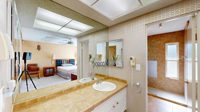 bathroom featuring ceiling fan, vanity, and a shower