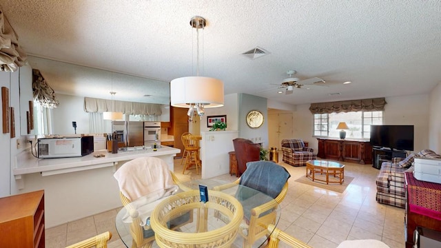 tiled dining space featuring ceiling fan and a textured ceiling