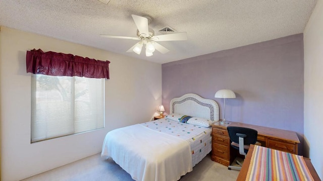 bedroom with ceiling fan, light colored carpet, and a textured ceiling