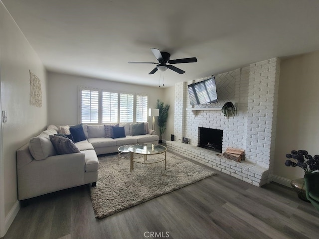 living room with ceiling fan, a brick fireplace, and dark hardwood / wood-style flooring