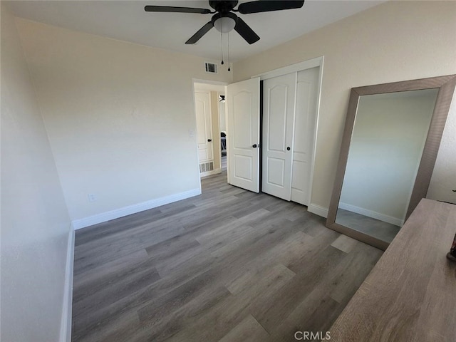 unfurnished bedroom featuring wood-type flooring, a closet, and ceiling fan