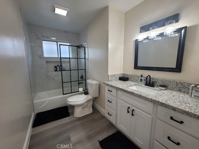 full bathroom with tiled shower / bath, vanity, toilet, and hardwood / wood-style floors