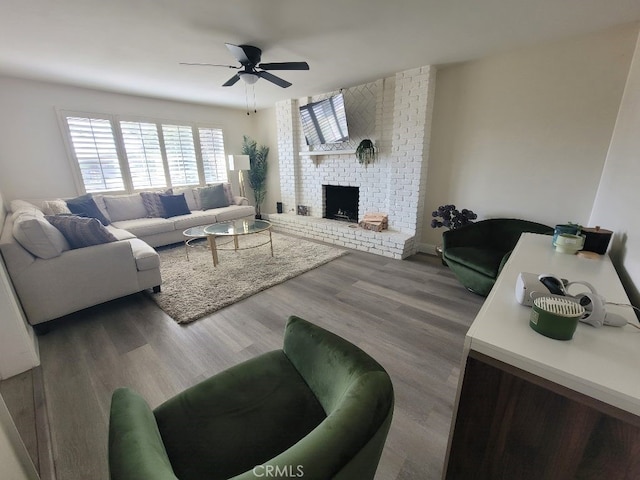 living room featuring hardwood / wood-style flooring, ceiling fan, and a brick fireplace