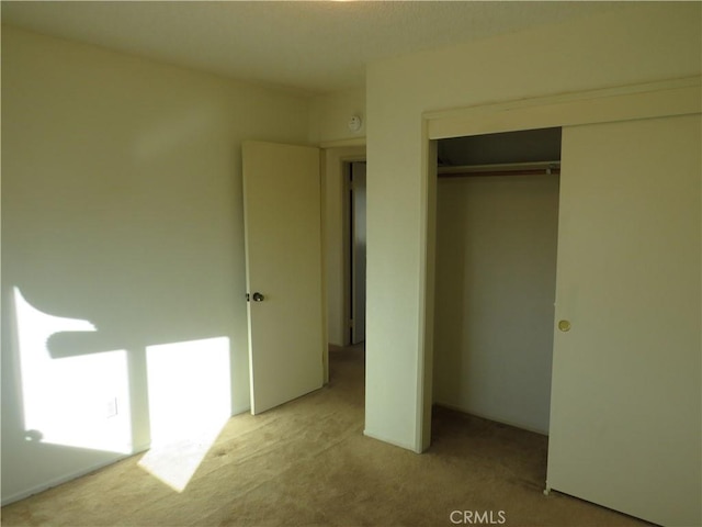 unfurnished bedroom with light colored carpet and a closet