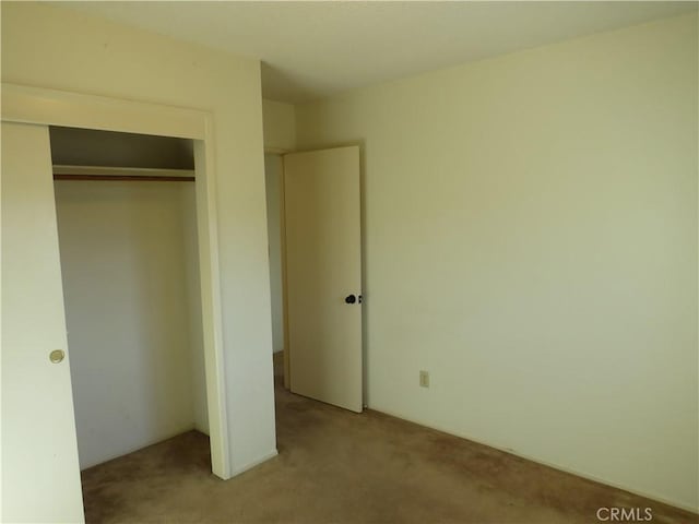 unfurnished bedroom featuring light colored carpet and a closet