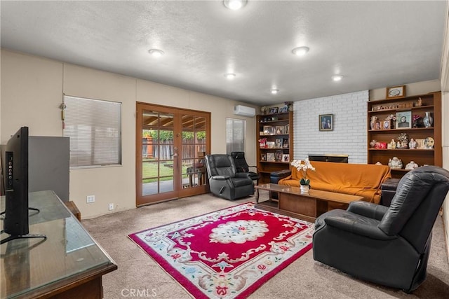 living room featuring a brick fireplace, a wall mounted air conditioner, carpet, and french doors