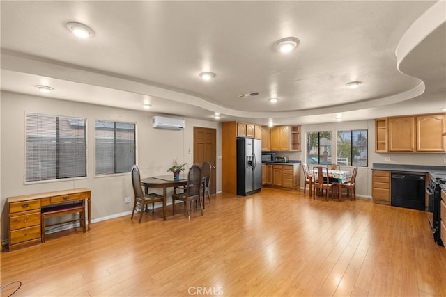 kitchen featuring a raised ceiling, light hardwood / wood-style flooring, a wall mounted AC, and black appliances