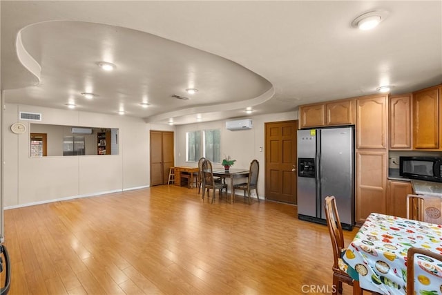 kitchen featuring an AC wall unit, light hardwood / wood-style flooring, and stainless steel fridge with ice dispenser