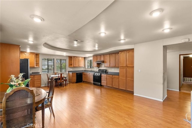 kitchen featuring range, light hardwood / wood-style flooring, stainless steel refrigerator, dishwasher, and a raised ceiling