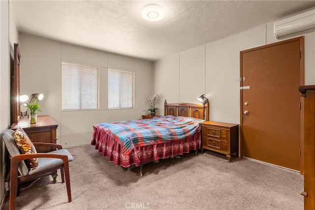 carpeted bedroom featuring a wall unit AC and a textured ceiling