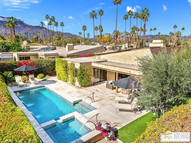 view of swimming pool featuring a mountain view, a patio, and an in ground hot tub