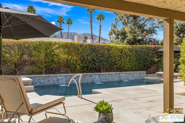 view of pool with a patio, a mountain view, and pool water feature