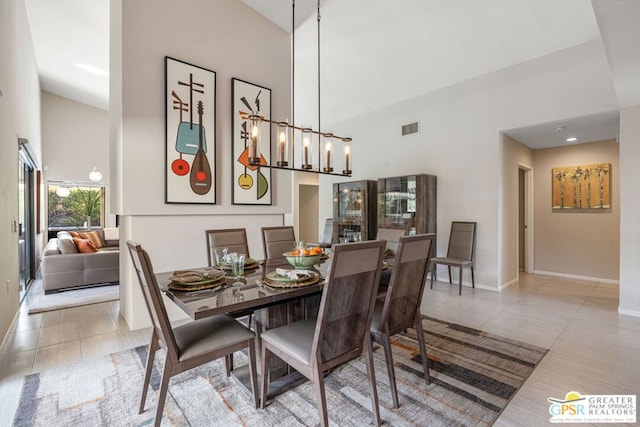 tiled dining area featuring a notable chandelier and a high ceiling