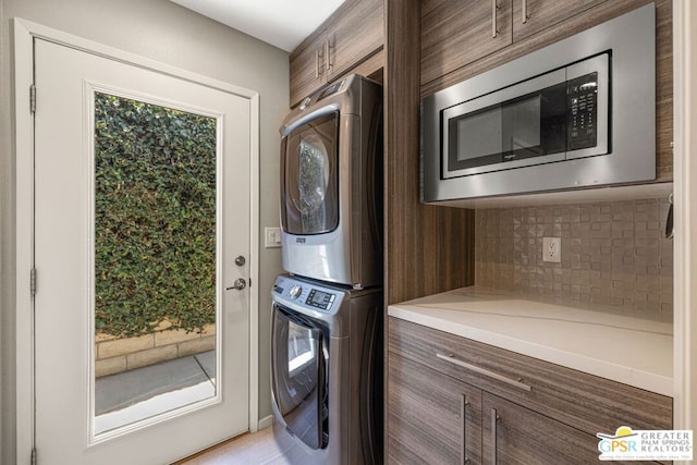 laundry room featuring stacked washer and dryer and cabinets