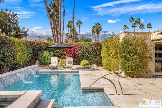 view of swimming pool with a mountain view, pool water feature, and a patio area