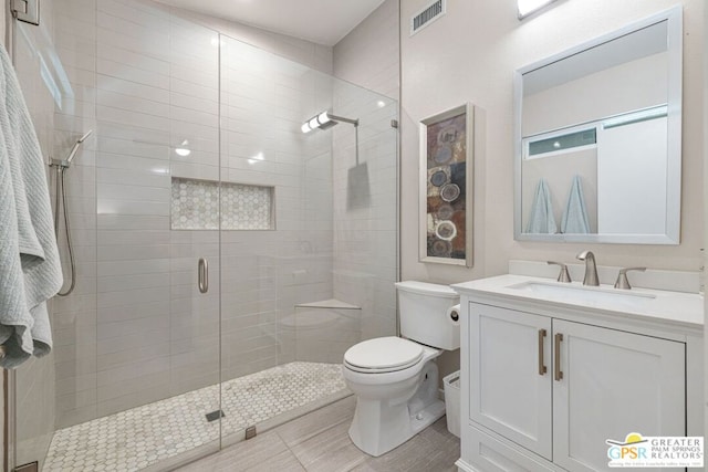 bathroom with walk in shower, tile patterned floors, vanity, and toilet