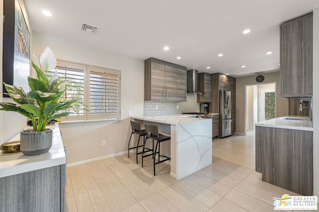 kitchen with a breakfast bar, stainless steel fridge with ice dispenser, sink, kitchen peninsula, and wall chimney exhaust hood