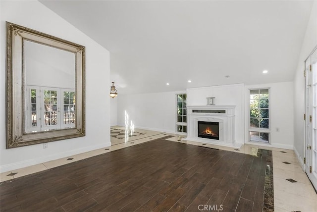 unfurnished living room featuring lofted ceiling, a high end fireplace, and wood-type flooring