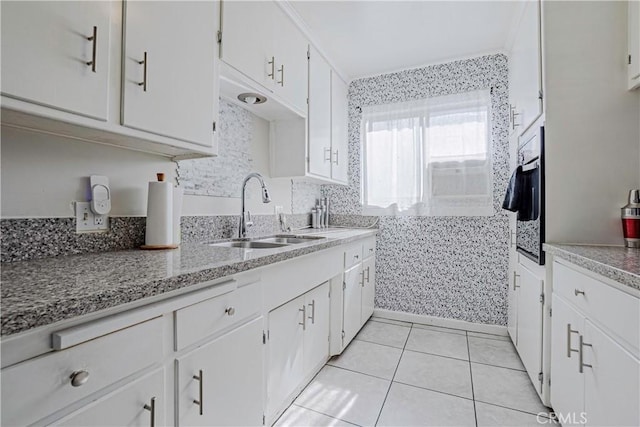 kitchen with white cabinetry, wall oven, light stone countertops, sink, and light tile patterned floors