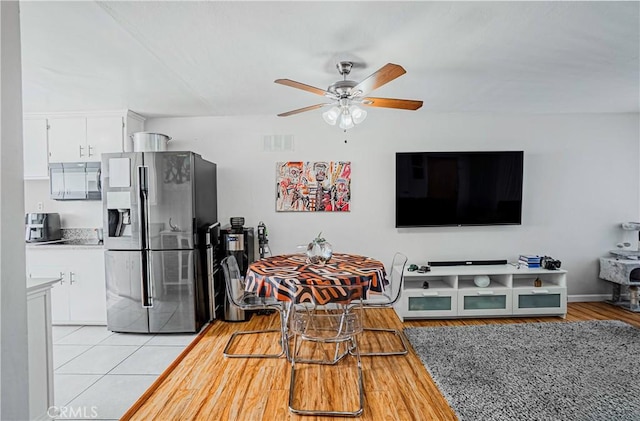 kitchen featuring white cabinets, light tile patterned flooring, stainless steel fridge, and ceiling fan