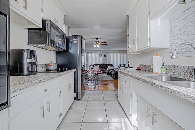 kitchen with ceiling fan, stainless steel refrigerator, light tile patterned floors, sink, and white cabinetry