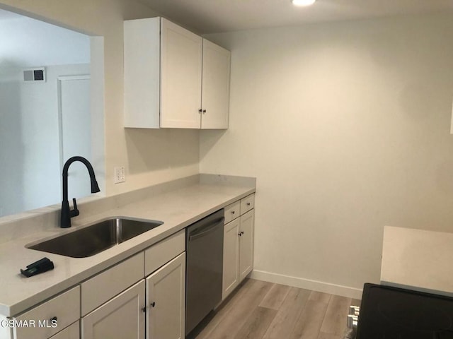 kitchen with white cabinetry, black dishwasher, sink, and light hardwood / wood-style flooring