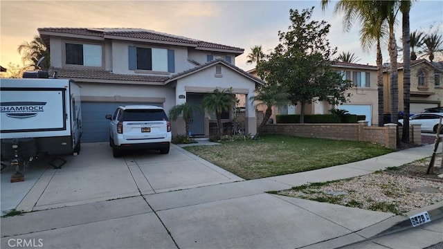 traditional-style home with driveway, a tile roof, an attached garage, a front lawn, and stucco siding