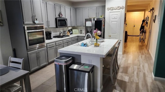 kitchen featuring appliances with stainless steel finishes, sink, a breakfast bar area, a kitchen island with sink, and light hardwood / wood-style floors