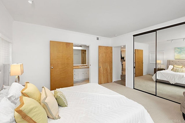 carpeted bedroom with ornamental molding, sink, ensuite bath, and a closet