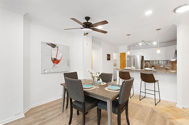 dining space featuring crown molding, light hardwood / wood-style floors, and ceiling fan