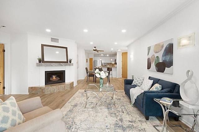 living room featuring crown molding, ceiling fan, and light hardwood / wood-style flooring